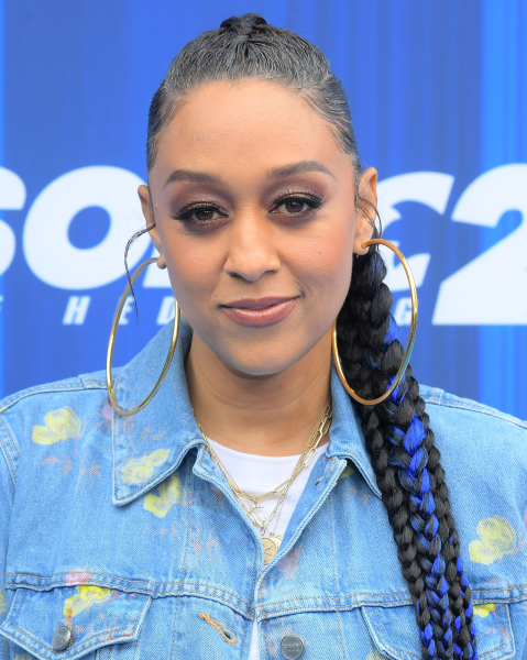 Tia Mowry wearing a bluestreaked braid and denim jacket